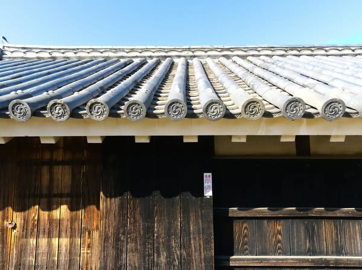 木の外壁の上に並ぶ瓦屋根の軒先